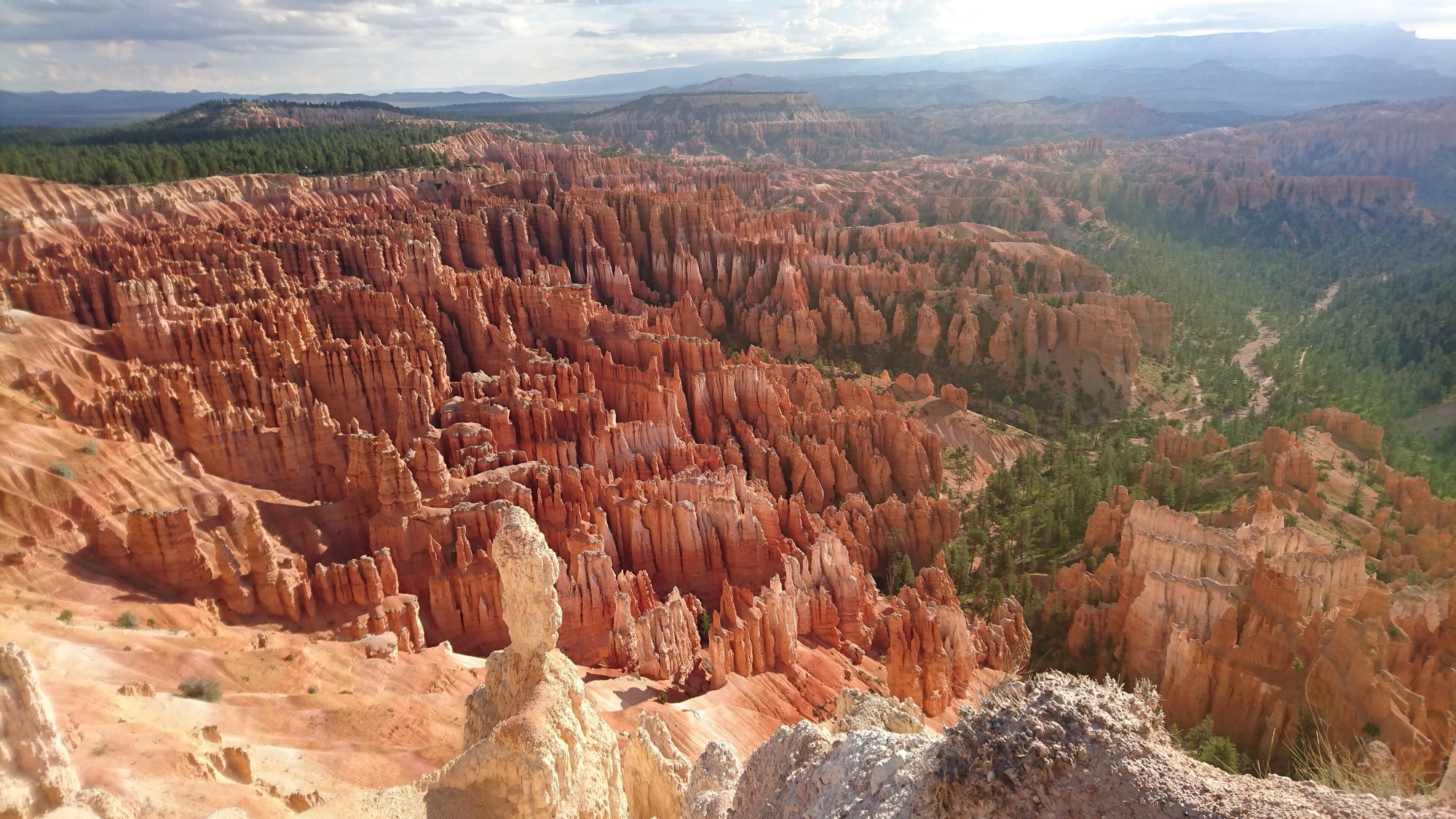 A wide vista of the orange hoodoo amphitheater at Bryce Canyon under a dramatic sky