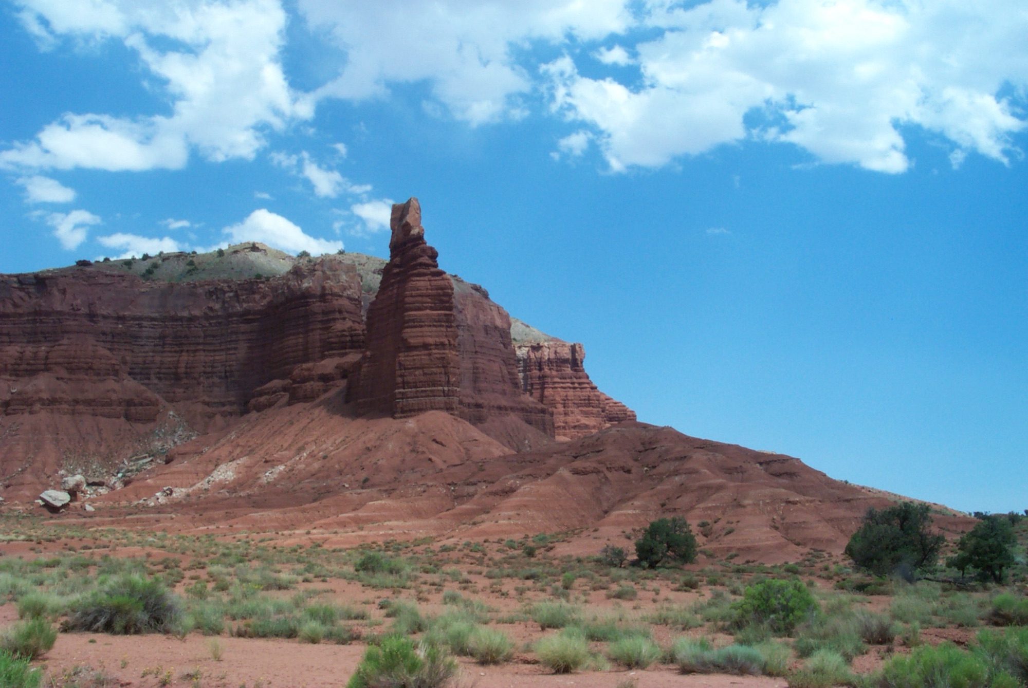 The Chimney Rock spire rising above red-rock badlands under a bright blue sky