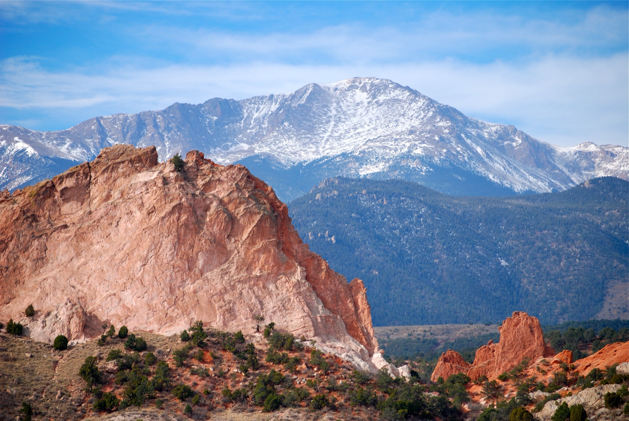 A red sandstone bluff in the Garden of the Gods with snow-capped Pikes Peak rising behind