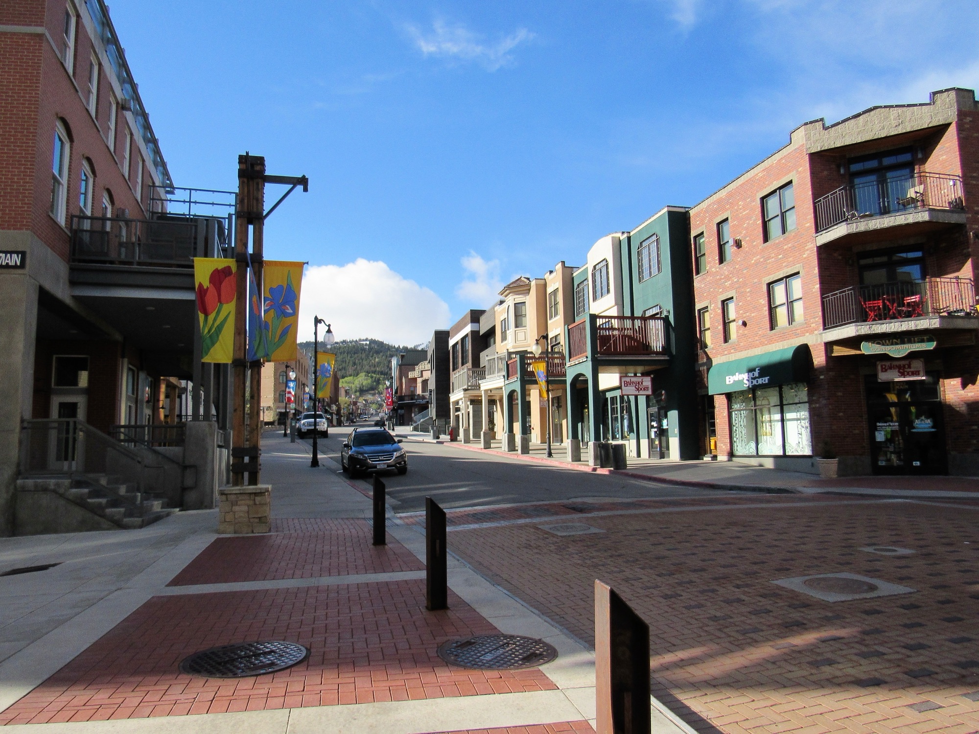 Historic Main Street in Park City under a blue sky, ski runs at the head of the street