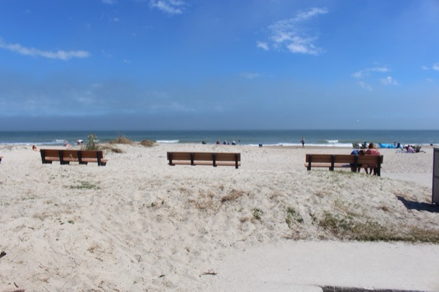A wide sandy Atlantic beach at Fernandina Beach on Amelia Island, with low grass-topped dunes under a blue sky