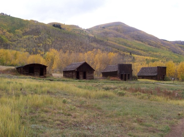 Weathered log cabins of the Ashcroft ghost town against golden autumn aspens