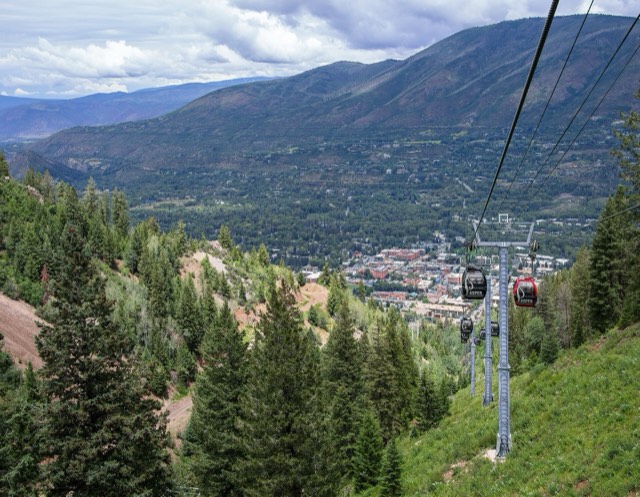 The Silver Queen Gondola cabins descending Aspen Mountain toward the town in the valley below