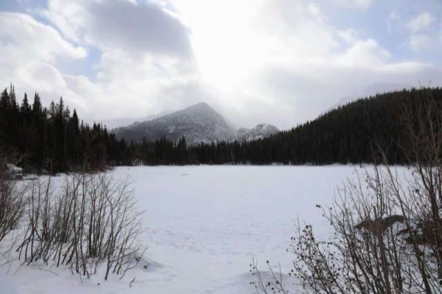 Frozen, snow-covered Bear Lake beneath cloud-wrapped peaks in winter