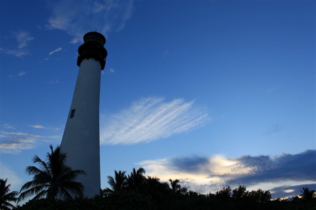 The white brick Cape Florida Lighthouse rising above palms at dusk at Bill Baggs Cape Florida State Park on Key Biscayne
