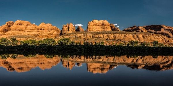 Red sandstone domes reflected in the calm Colorado River near Moab