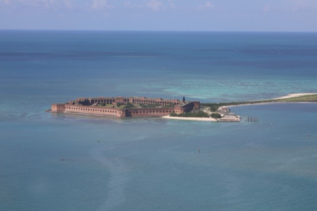 An aerial view of the massive red-brick Fort Jefferson on Garden Key in Dry Tortugas National Park, ringed by white sand and turquoise Gulf water