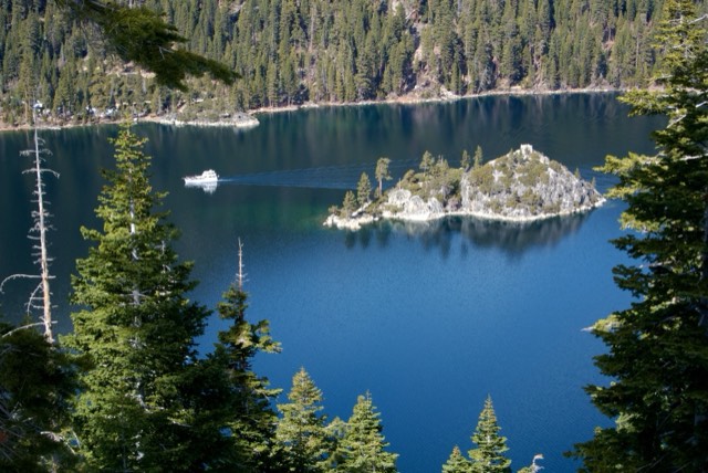 Fannette Island sits in the deep-blue water of Emerald Bay, a small boat nearby giving scale.