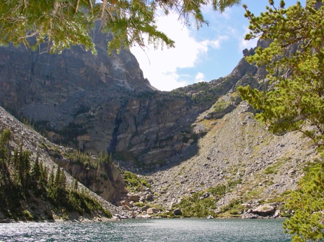 The cirque headwall rising above Emerald Lake, framed by pines