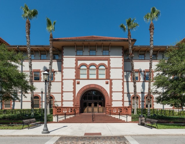 The historic Proctor Library at Flagler College, framed by palms under a blue sky