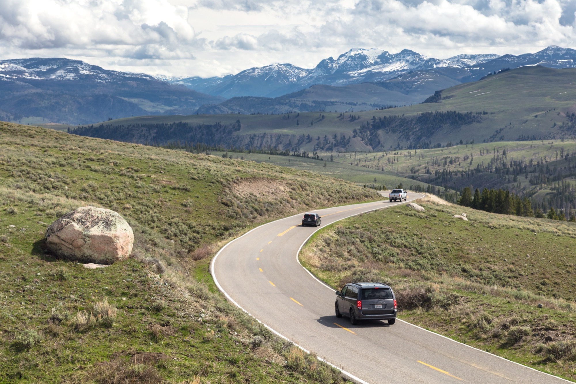 The Grand Loop Road winding through a valley toward snowy peaks