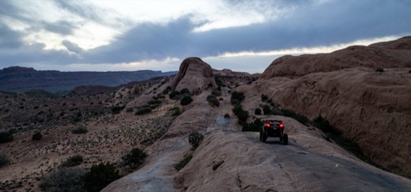 Slickrock and off-road vehicles on the Hell's Revenge 4x4 trail at dusk near Moab