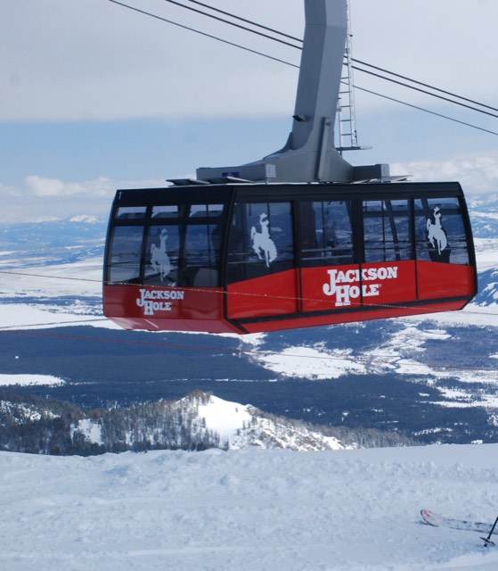 The red Jackson Hole aerial tram car rising over the snowy valley