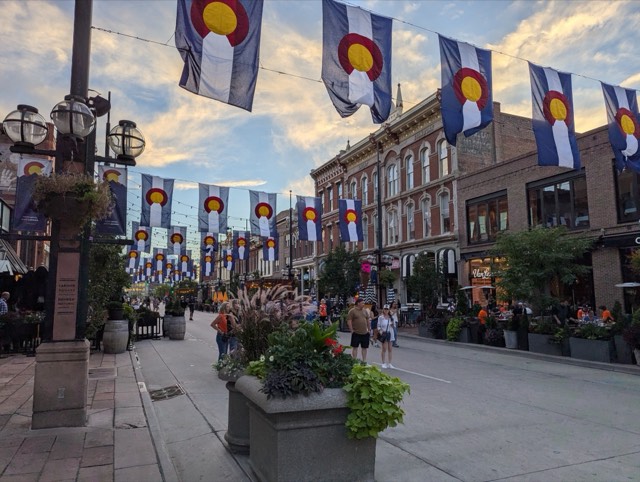 Colorado state flags strung across historic Larimer Square at golden hour