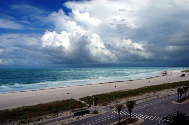 The wide white-sand beach at Lido Key in Sarasota, with Gulf waves rolling in under a dramatic cloudy sky