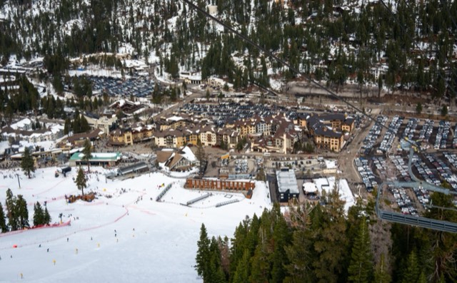 Elevated view of the Palisades Tahoe village and ski lifts below the Olympic Valley peaks.
