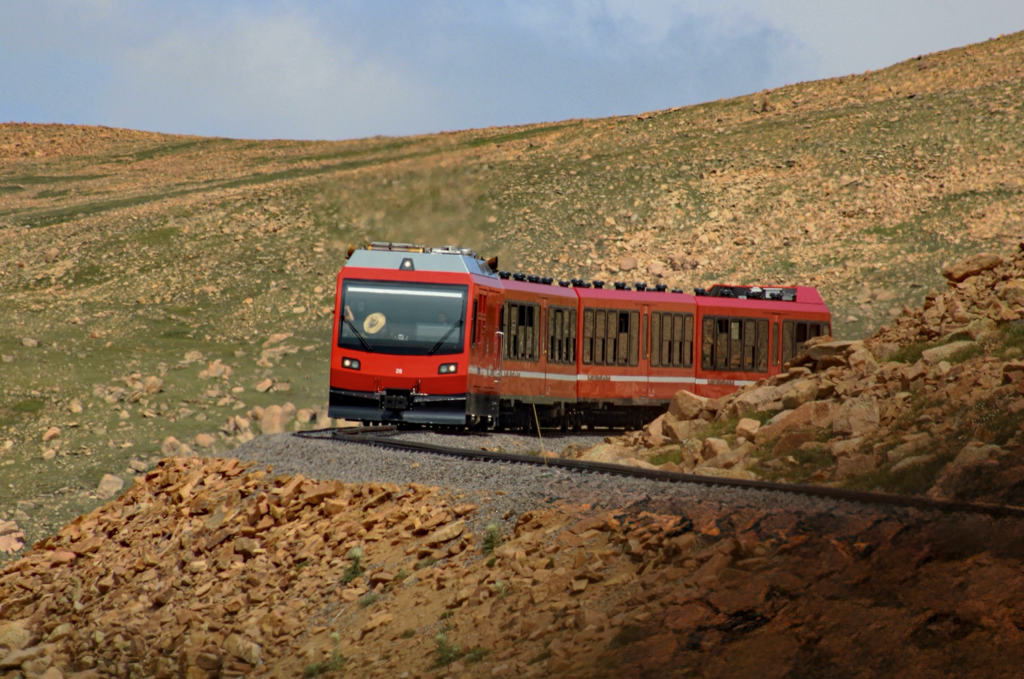 A red cog railway train climbing the alpine grade near the summit of Pikes Peak