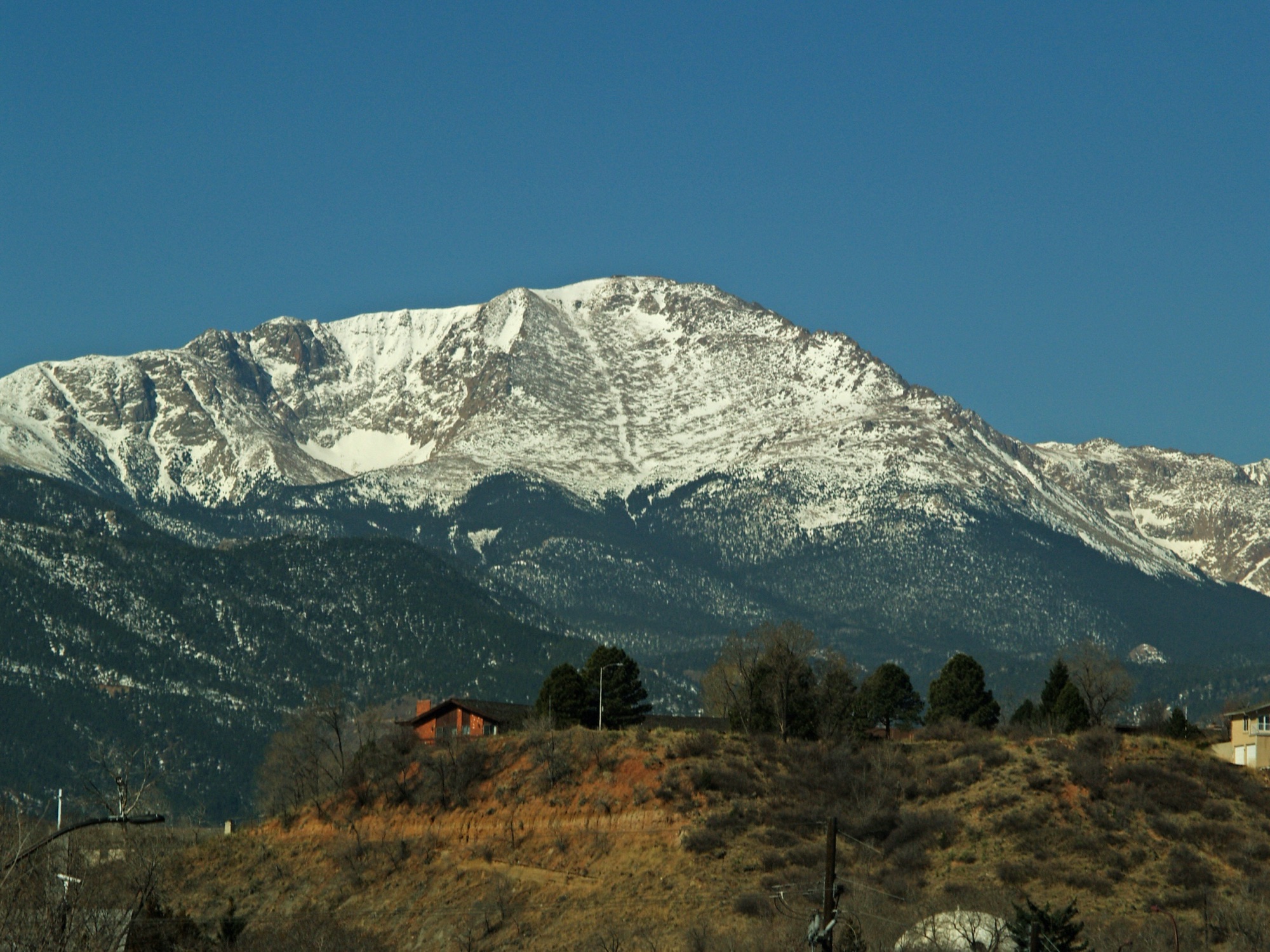 The snow-capped summit of Pikes Peak under a deep blue sky