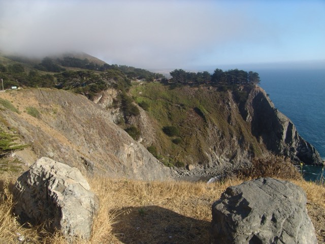 The tree-topped Ragged Point headland dropping to the ocean at Big Sur's southern gateway, fog rolling in