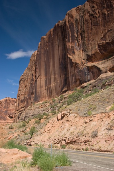 A towering red cliff wall above Highway 128, the Colorado River Scenic Byway
