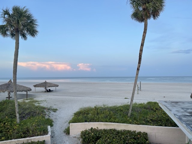 The fine white quartz sand and calm turquoise Gulf water of Siesta Beach on Siesta Key in Sarasota, framed by palms at dusk