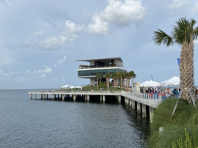 The modern inverted-pyramid pier-head building of the St. Pete Pier extending over Tampa Bay