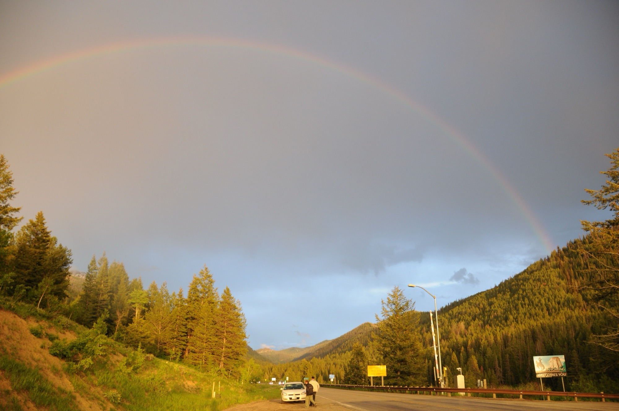 A rainbow over the road climbing forested Teton Pass