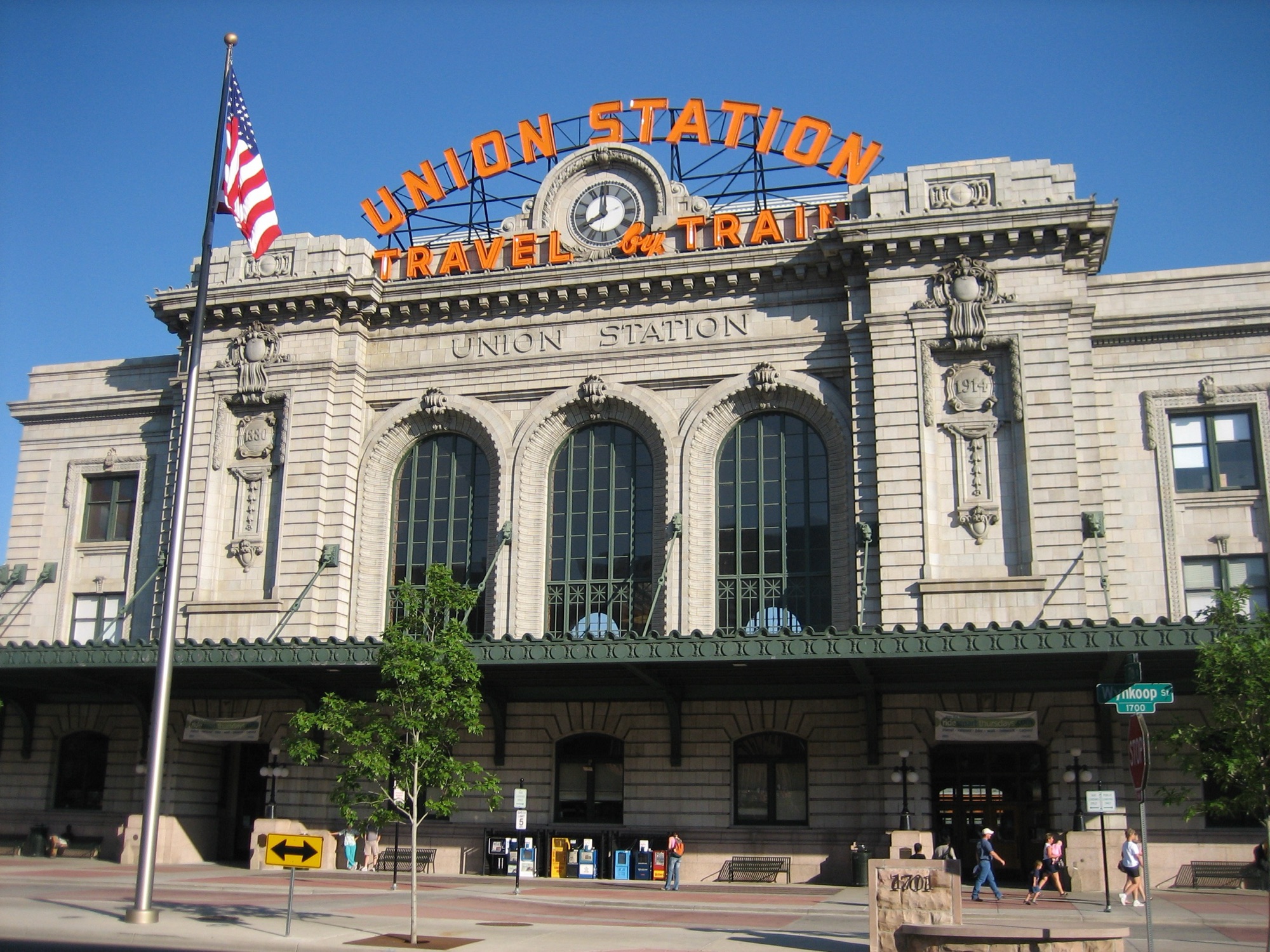 Denver Union Station's Beaux-Arts facade beneath its landmark 'Travel by Train' neon sign