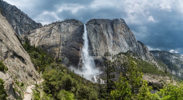 Upper Yosemite Falls in full flow under a dramatic sky, seen from the Yosemite Falls trail