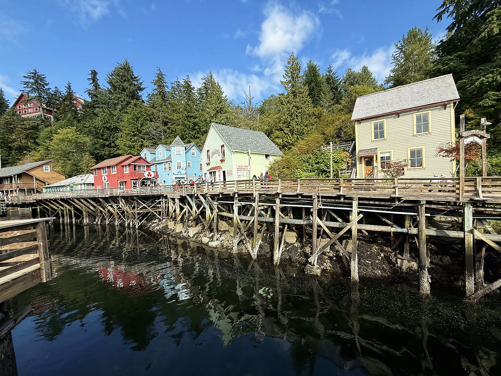 Creek Street in Ketchikan — a row of colorful historic buildings on stilts reflected in the calm creek