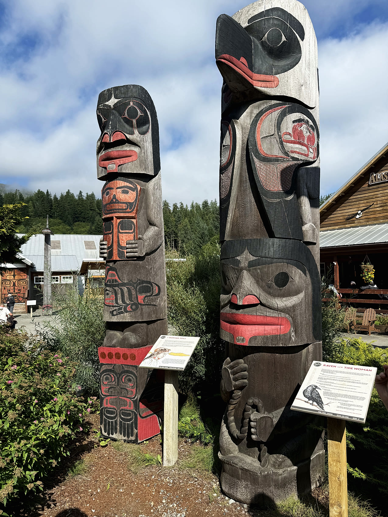 Two carved and painted totem poles with clan figures at a Ketchikan totem park
