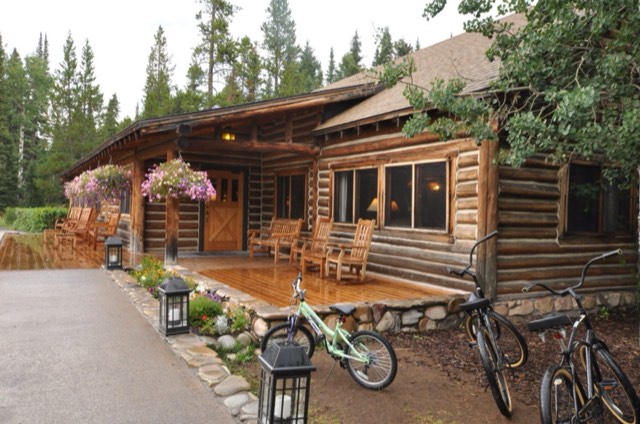 A rustic log cabin with rocking chairs and flower baskets at Jenny Lake Lodge