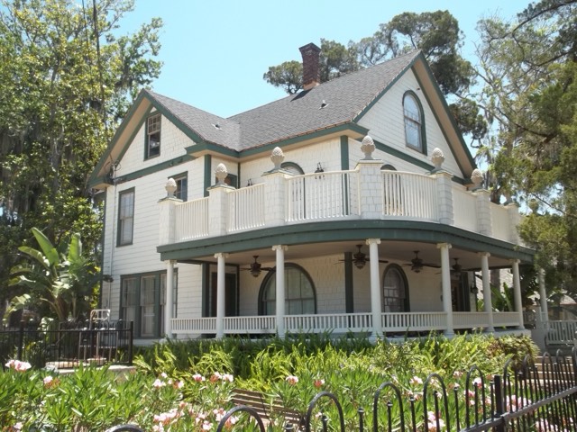 One of the restored Victorian houses at The Collector Luxury Inn & Gardens — white clapboard with a wraparound porch and lush garden in St. Augustine