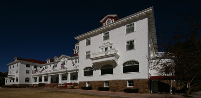 The white Georgian facade of the historic 1909 Stanley Hotel against a deep blue sky