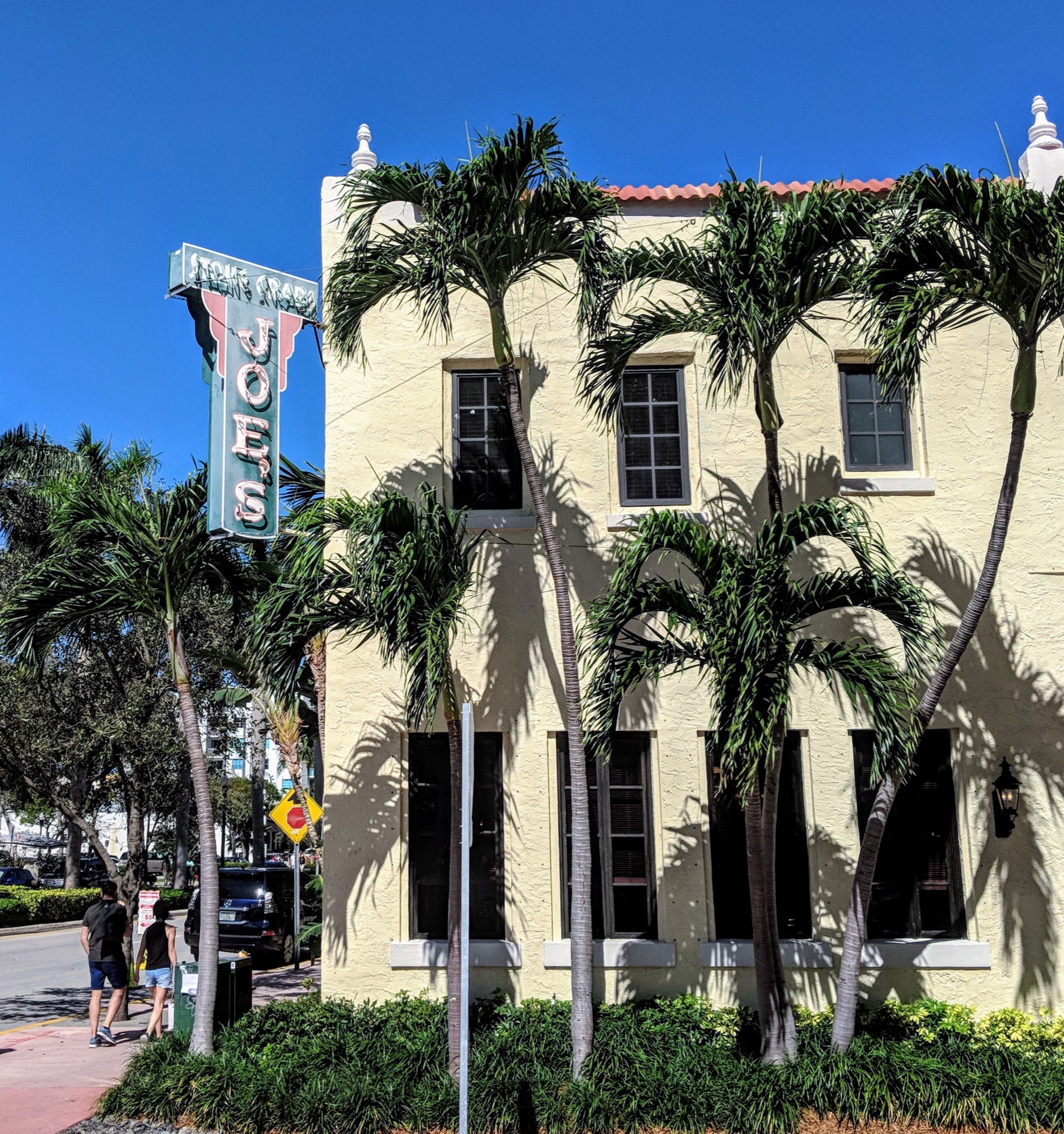 Joe's Stone Crab — the historic 1920s Mediterranean building and vintage neon sign framed by royal palms in South Beach