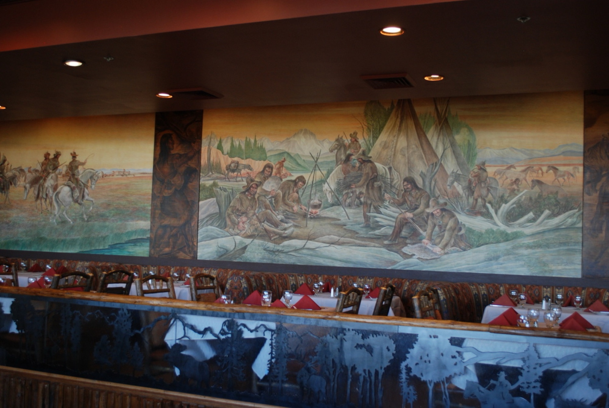 The historic Western murals and set tables of the Mural Room at Jackson Lake Lodge